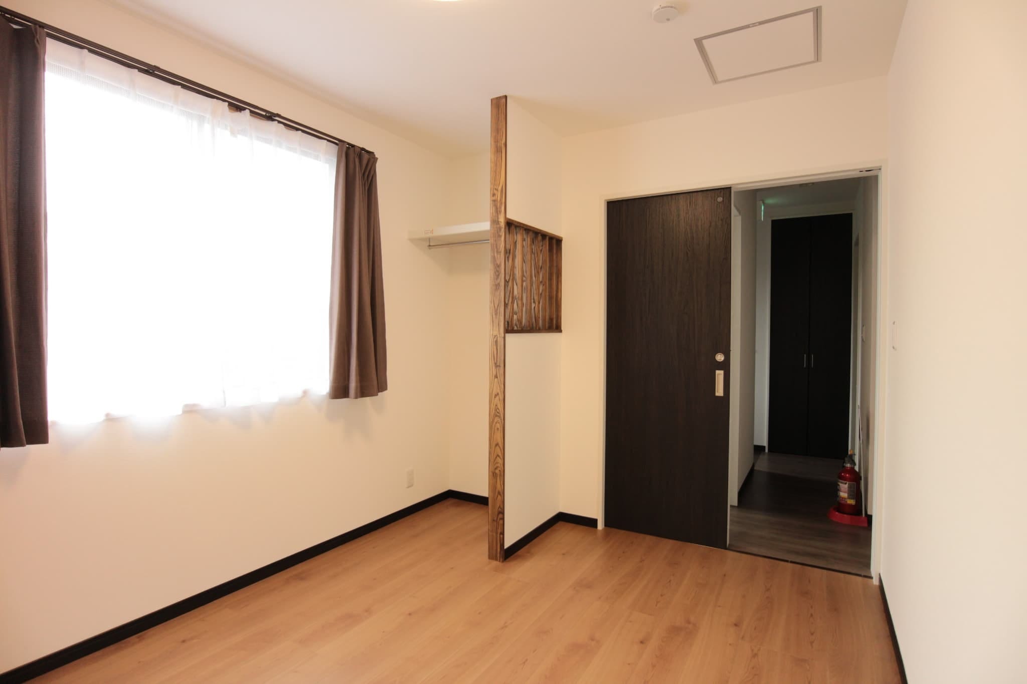 こちらが利用者様の個室です。収納として、棚とハンガーパイプを設置した間仕切りは、依頼主様のイメージ写真をいただき、それに合うようオリジナルで弊社の大工が7部屋分製作しております。
また、ご依頼主様のご希望で部屋ごとにフローリングの色を変えたため、全部で4色のフローリングの部屋があります。