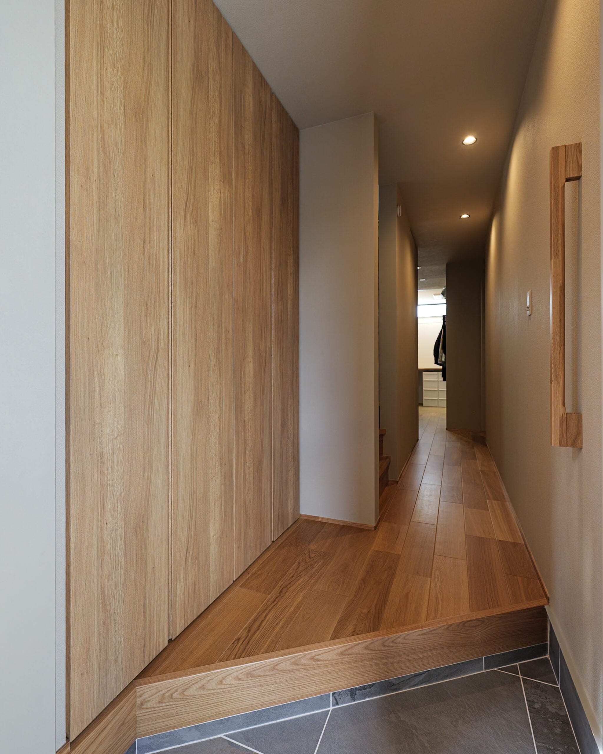 木目の美しさが際立つ玄関ホールは、落ち着きと上質さを感じるグレージュトーンで統一。すっきりと伸びる動線が奥行きを生み、帰宅後すぐにホッとできる落ち着いた雰囲気に。素材の温もりを大切にした、心地よい暮らしの入り口です。