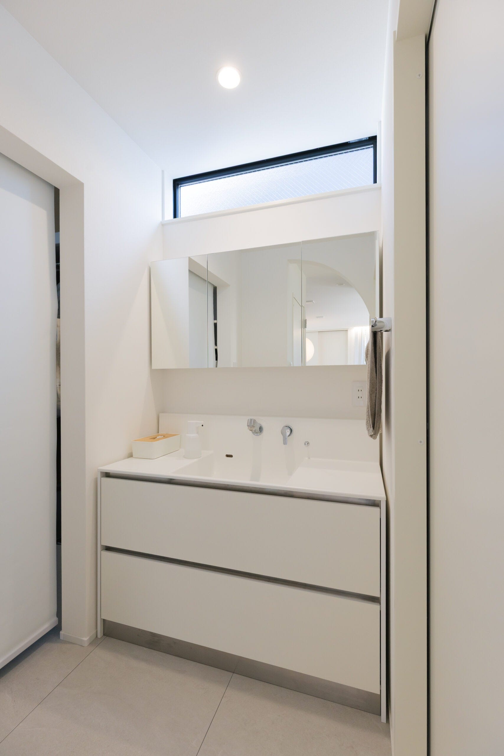 ホワイトでまとめた洗面台は部屋全体を明るい雰囲気に。壁から壁へとのびる鏡が使いやすさと空間を広く見せる2つの効果を発揮しています。上部のFIX窓で朝の支度を自然光で出来るのは嬉しいポイント。