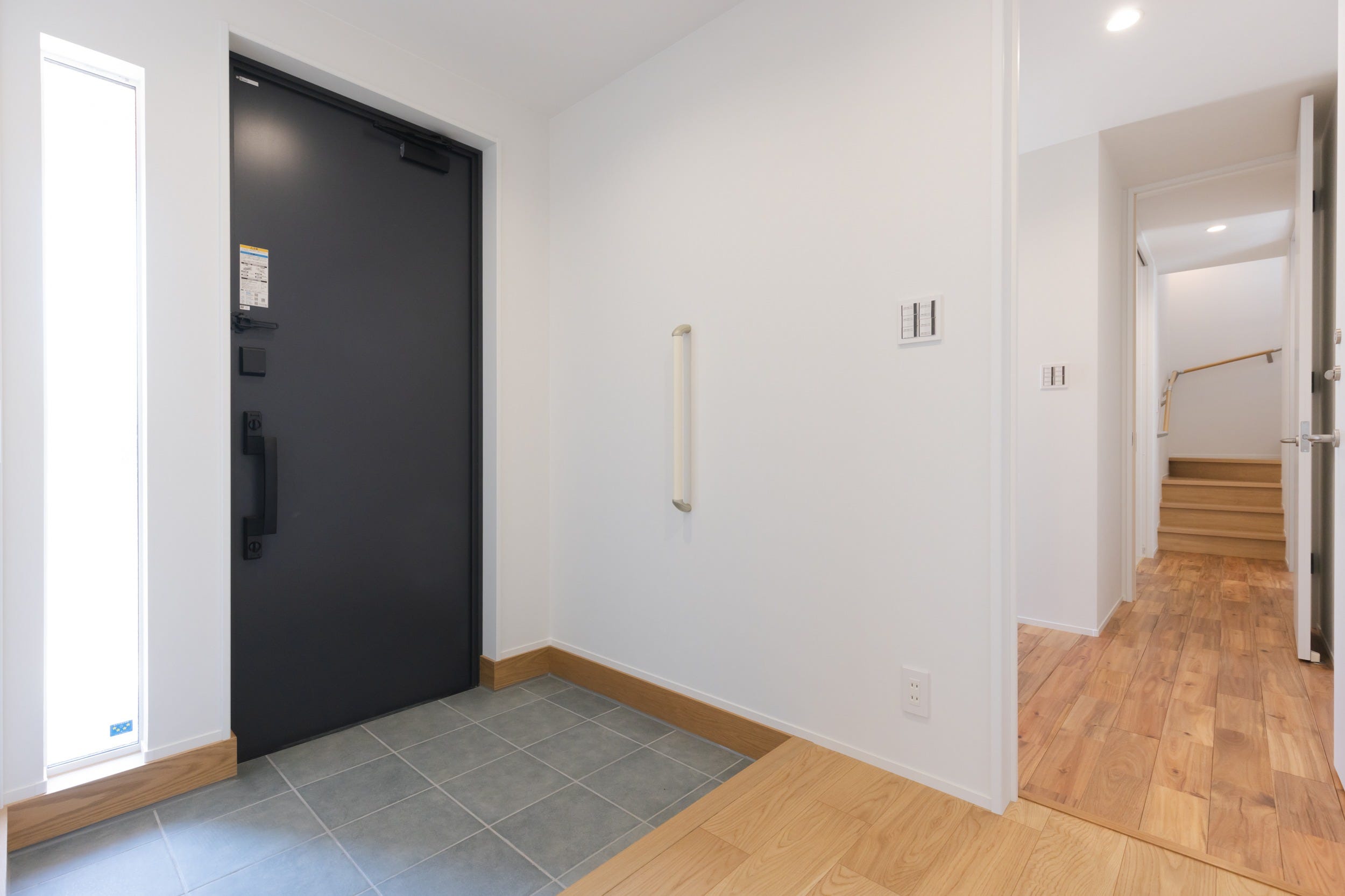 〈親世帯様からの玄関の景色〉世帯の間では、扉を設けプライバシーを保つことができる。縦長のFIX窓を設置したことで、玄関が明るくお客様をお迎えする