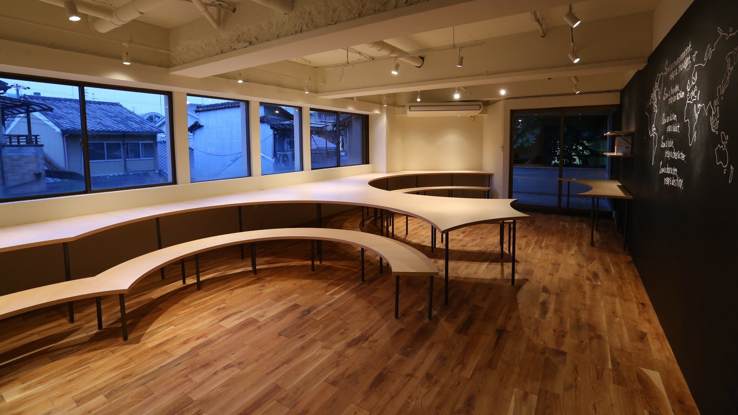 StudyRoom(学習塾) (「StudyRoom」は個別指導方式の学習塾です。本校ではブースごとに細かく区画された閉鎖的な教室ではなく、集中しつつも適度にリラックスできる開放的な学習環境が求められました。また授業のない昼間はワークショップやイベントなどが積極的に行なわれ、コミュニケーションの場としての役割も担います。そこで大小いくつかの円で切り取られた大テーブルによるワンルーム空間を提案。オープンスペースでの学習は他者の存在を意識することにより集中力を持続させる効果が生まれます。また、座席はフリーアドレスとすることでさまざまなシーンにフレキシブルな対応が可能となり、学習の場のみならず人と人との交流の中で育まれる本質的な教育の場となることを期待しています。)