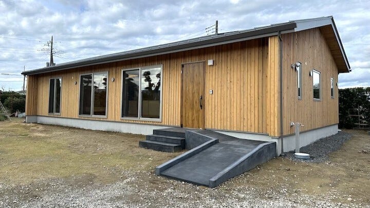潮来の家 (本計画地には元々築年数が不明の古民家が建っていた。現地調査の段階では既に増築やリフォームを数回繰り返されていたが、半世紀ほど前には土間の台所や薪釜、離れに厠や五右衛門風呂などがあったとの事。
残念ながら東日本大震災では建物に大きなダメージを受け、害虫被害も見受けられていたことから今回建替える事とした。
計画当初から大黒柱をはじめ、なるべく古材を再利用する方向で検討していたが、解体が始まった際に確認したところ想像以上に虫食いが酷く、利用できる部分は室内に露出していた部材のみ。結果として使えそうな部分から厳選して再利用する事とした。
玄関ドアを開けると広い玄関土間が続き、再利用された太い大黒柱や梁が存在感を示す。また室内建具で使用されていた組子細工も当時と同じ建具職人の手により新しく生まれ変わらせた。
以前の建物の存在を継承しつつ、世代を超えてもその歴史を受け継いでいく。そして高気密高断熱住宅として生まれ変わったこの家は、家族が家の中心に自然と集まる空間とし、快適な生活とともにまた新しい歴史が刻まれていく。)