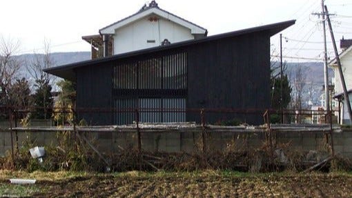 薪ストーブのある終の住処／佐久平の家・A邸 (これは、長い都会生活の後に、田舎に終の住処を求めた老夫婦のための住宅です。幼少期をこの辺りで過ごした建主が手に入れたのは、100坪の宅地と100坪の耕地。ここは、積雪はないものの厳しい冬季と快適な夏季を過ごすことができる土地です。ですから退屈な毎日を枯れていくように過ごすのではなく、四季を満喫しながら、家庭菜園を楽しみ、友人や家族が集うことのできる住宅を実現しています。
冬季には厳しい寒さが訪れるこの辺り。基礎を含め地元の工務店とも検討した寒冷地仕様の床・壁・天井とし、そこに床暖房と薪ストーブを導入しています。薪ストーブが置かれた土間スペースは、家庭菜園のための作業場であり釣りが趣味の建主の作業場でもあります。冬季は太陽光が差し込み暖かさを蓄えてくれます。長期の休暇時期には遠方から娘夫婦や孫たちが訪れ賑やかとなります。そうしたときには畳室とロフトスペースが活躍します。夏季には風の抜ける平屋ならではの快適さが来客を誘います。
シンプルな構成にシンプルなデザインは、骨太な田舎暮らしを快適に過ごすための選択です。)